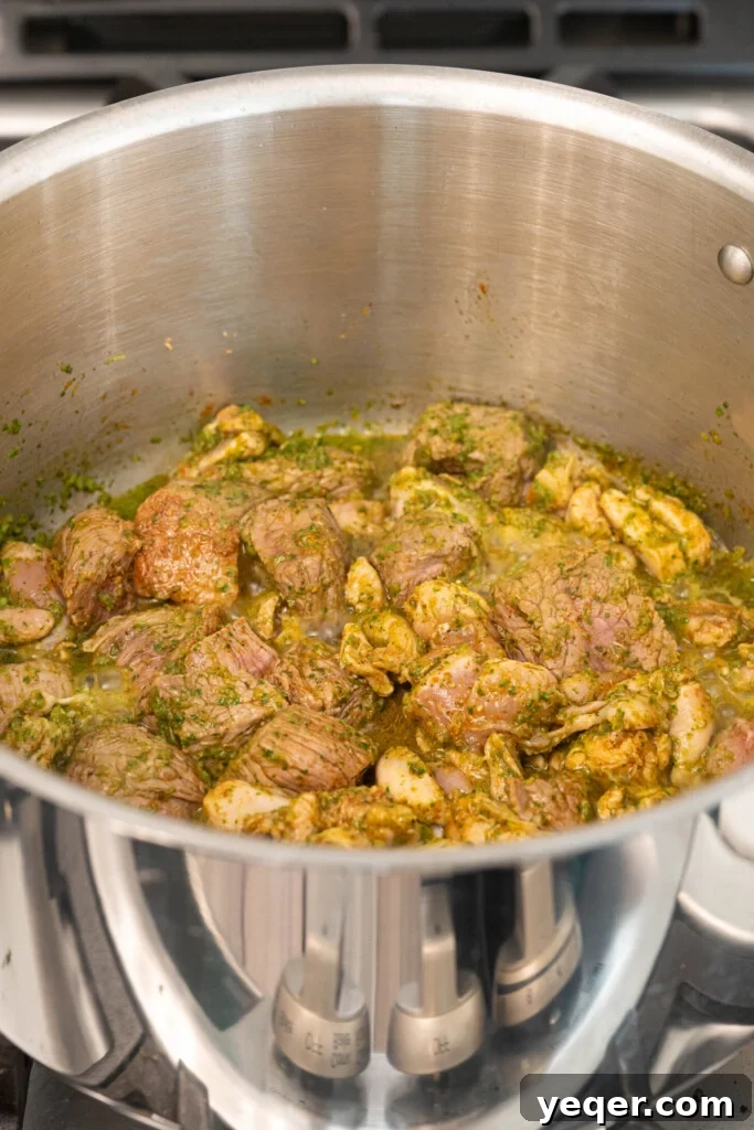 Rich Puerto Rican Sancocho Beef and Root Vegetable Stew 4 A large pot on a stovetop, filled with beef and chicken pieces browning with sofrito and seasonings, emitting steam and rich aromas.