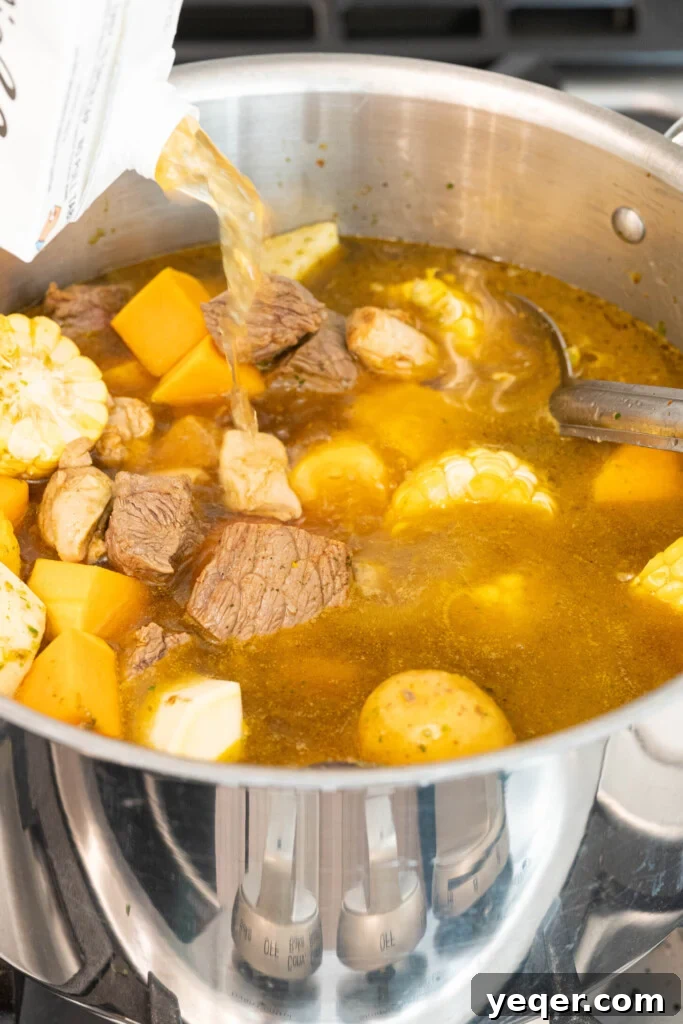 Rich Puerto Rican Sancocho Beef and Root Vegetable Stew 6 A hand pouring broth into a pot filled with browned meat and a colorful assortment of root vegetables, ready for simmering.