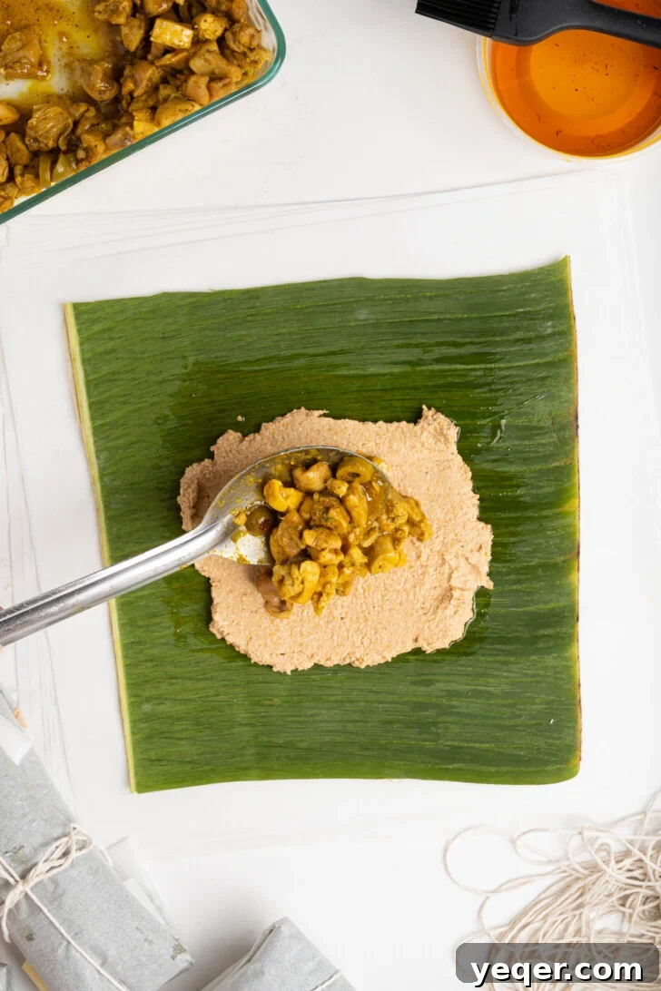 Puerto Rican Pasteles: Savory Meat-Stuffed Masa Delights 14 A dollop of meat filling being placed on an oval-shaped masa spread on a banana leaf.