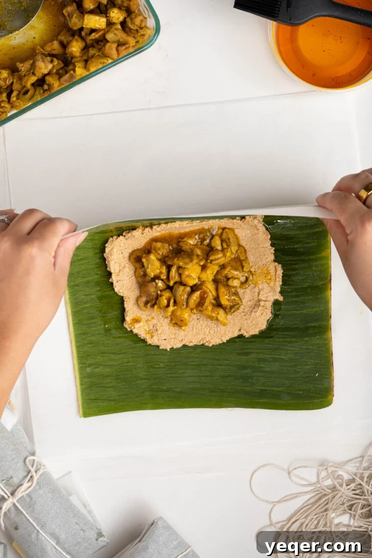 Puerto Rican Pasteles: Savory Meat-Stuffed Masa Delights 15 A pastel being folded in half, bringing the banana leaf and parchment paper together.