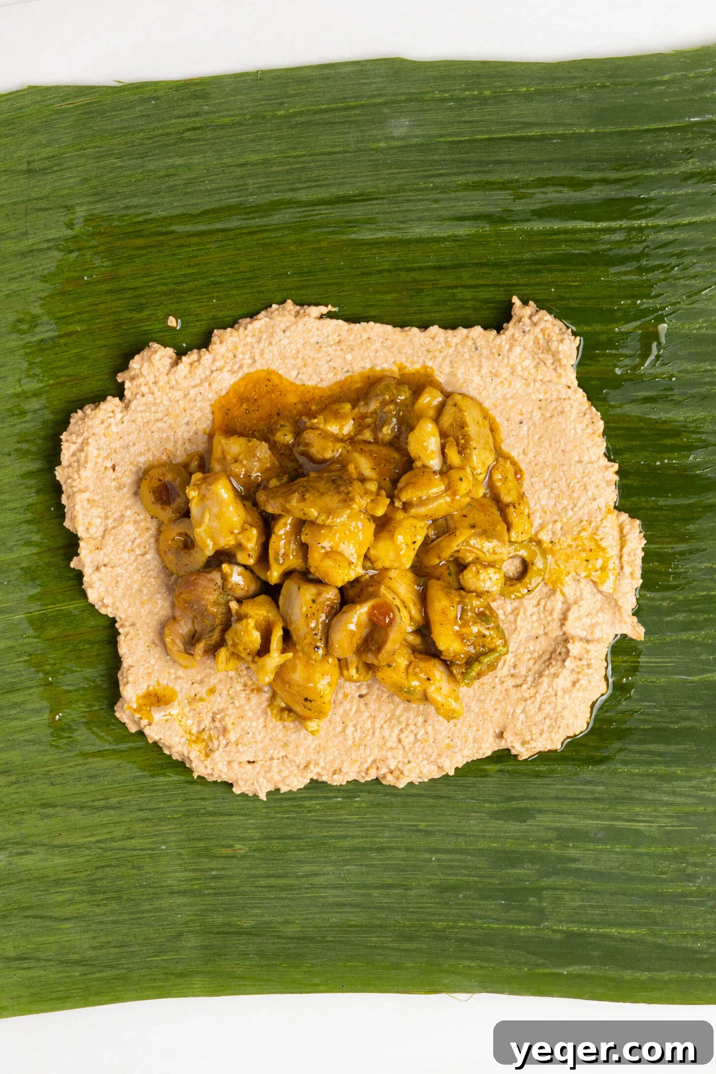 Puerto Rican Pasteles: Savory Meat-Stuffed Masa Delights 25 A close-up view of chicken filling being placed on the masa, ready for folding.