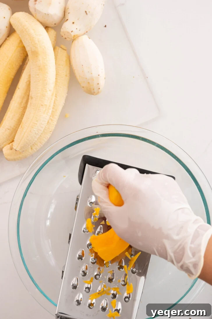 Puerto Rican Pasteles: Savory Meat-Stuffed Masa Delights 10 A person grating squash into a large bowl using a box grater.
