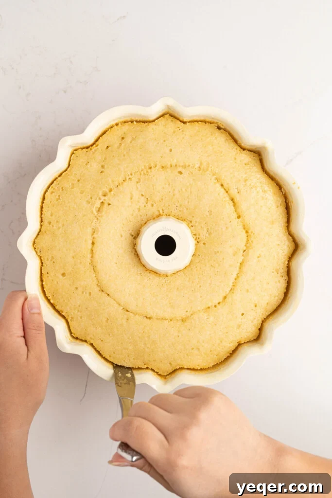 Puerto Rican Flancocho: Vanilla Cake and Creamy Flan Fusion 12 A knife gently loosening the edges of the baked Flancocho from the bundt pan before flipping.