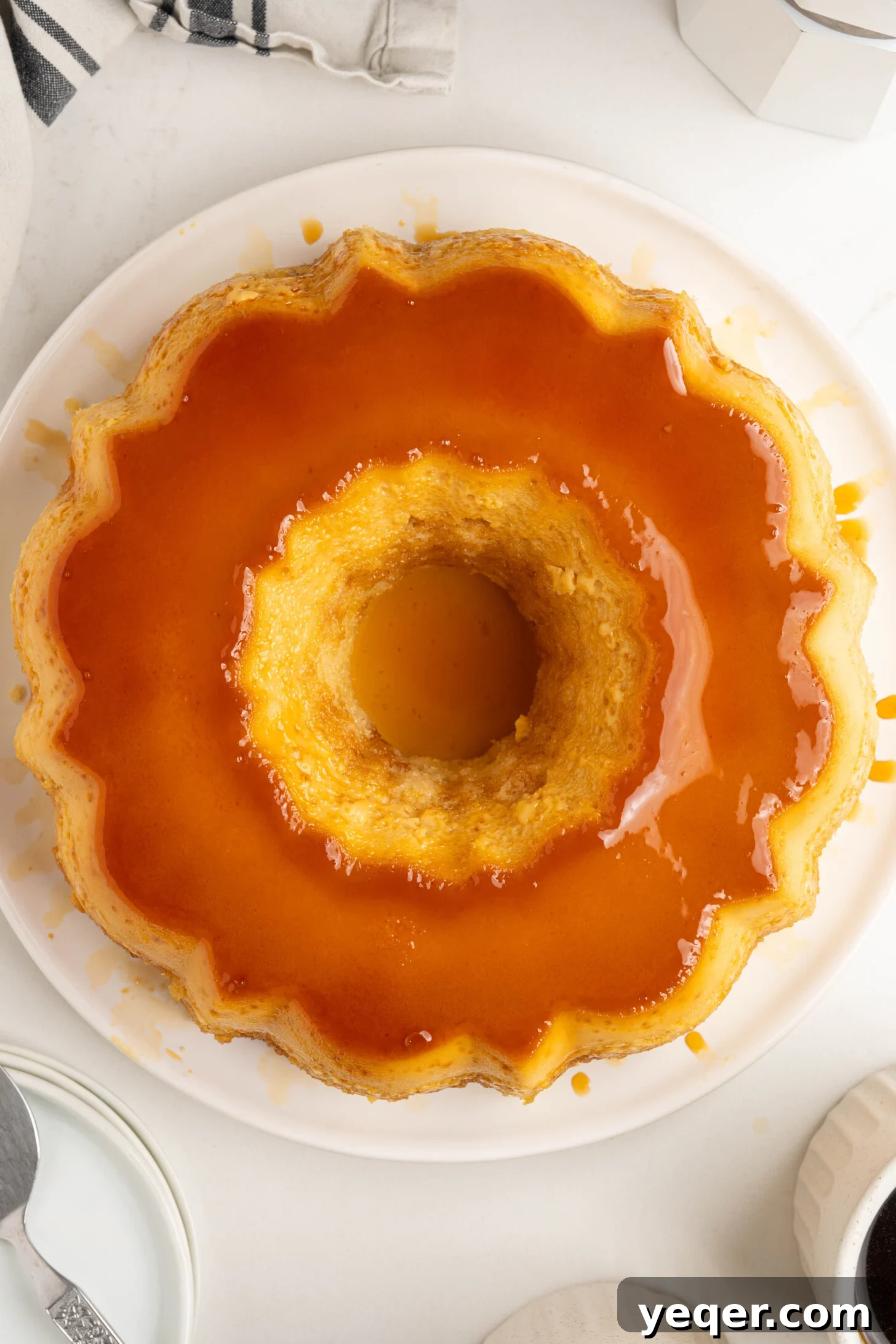 Puerto Rican Flancocho: Vanilla Cake and Creamy Flan Fusion 15 A whole Flancocho dessert on a white serving platter, beautifully glazed with caramel.