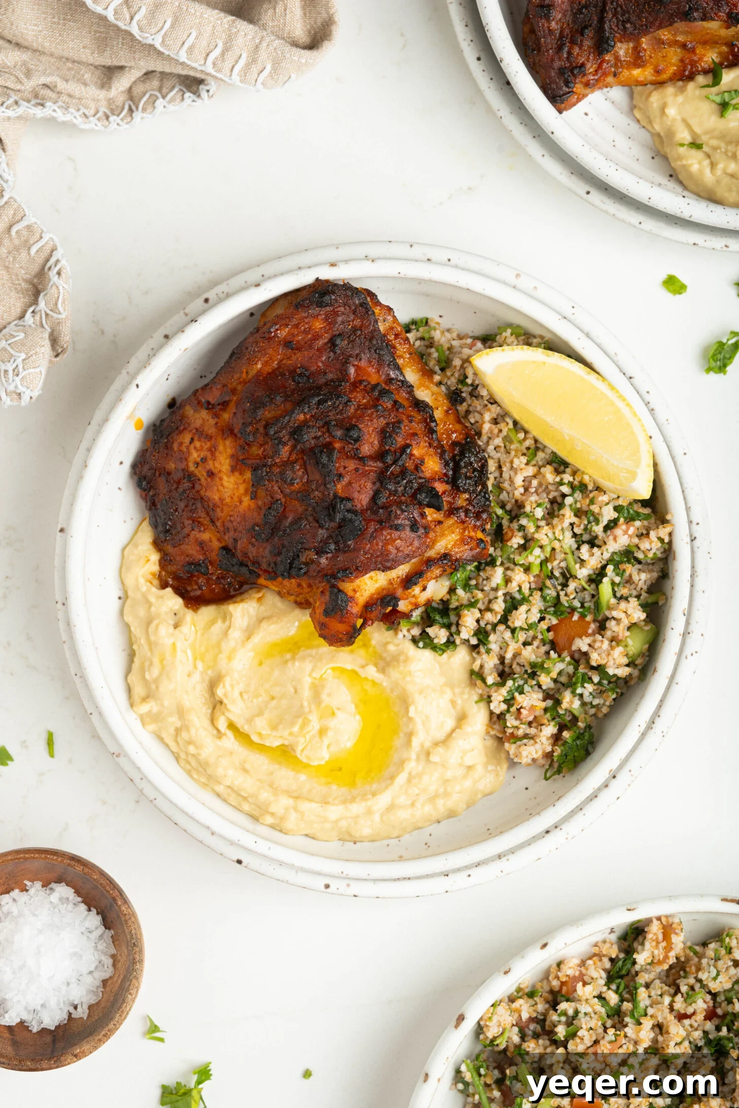 Fast & Flavorful Harissa Roasted Chicken Thighs 8 A succulent harissa chicken thigh served with creamy hummus and a fresh green salad, embodying a perfect balance of flavors and textures.