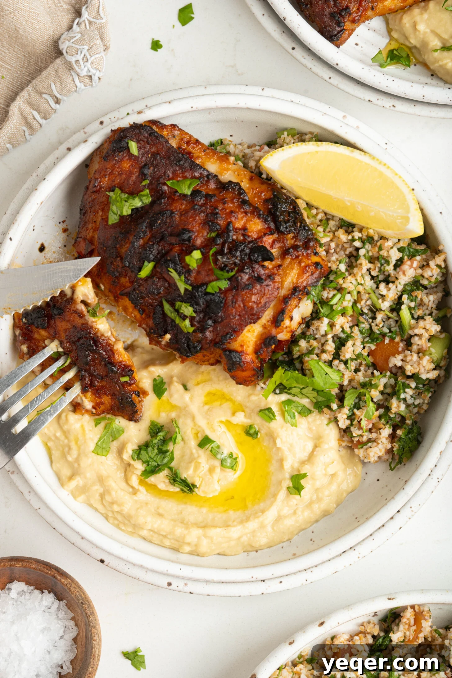 Fast & Flavorful Harissa Roasted Chicken Thighs 10 A beautifully arranged serving of harissa chicken thigh, accompanied by creamy hummus and a fresh, vibrant side salad.