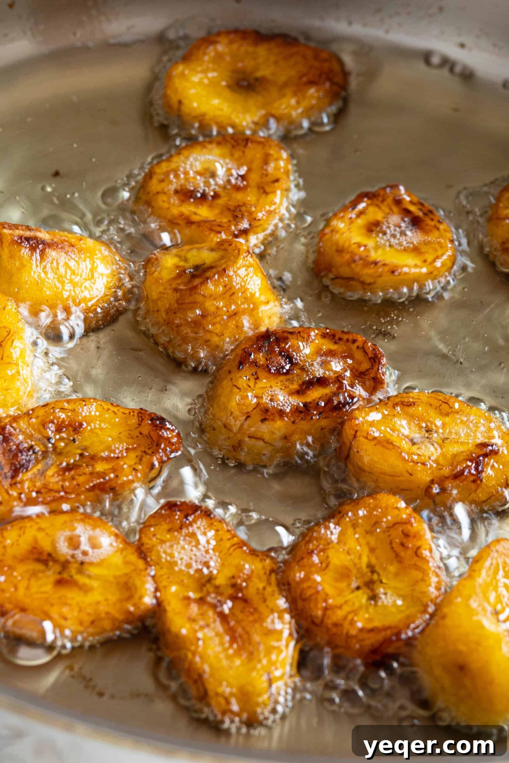 Master the Art of Peeling Any Plantain 8 Slices of sweet plantains (maduros) gently frying in a pan until golden and caramelized.