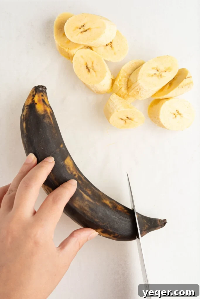 Master the Art of Peeling Any Plantain 4 A hand using a sharp knife to carefully slice off the end of a brown plantain.