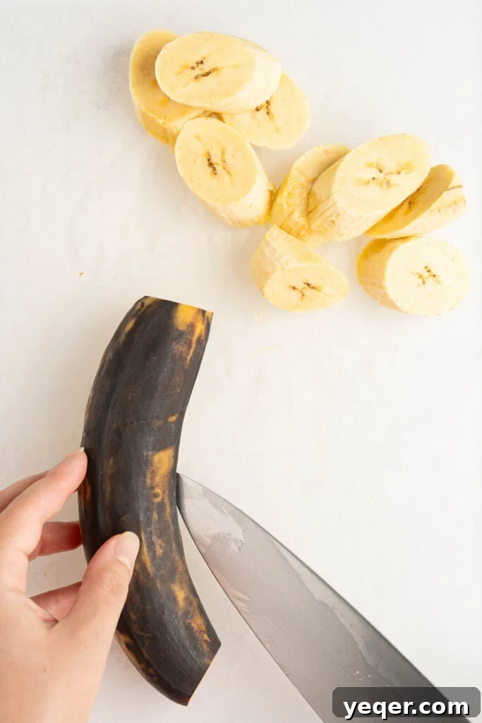 Master the Art of Peeling Any Plantain 5 A knife making a shallow, lengthwise incision along the peel of a brown plantain.