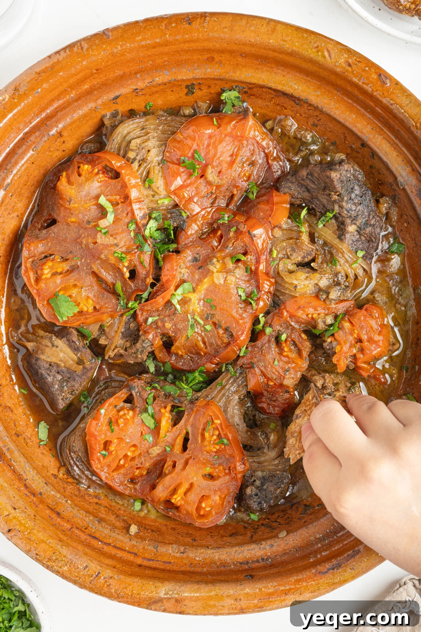 Rich Moroccan Beef Tagine with Tomatoes and Onions 14 a hand scooping up Moroccan beef tagine