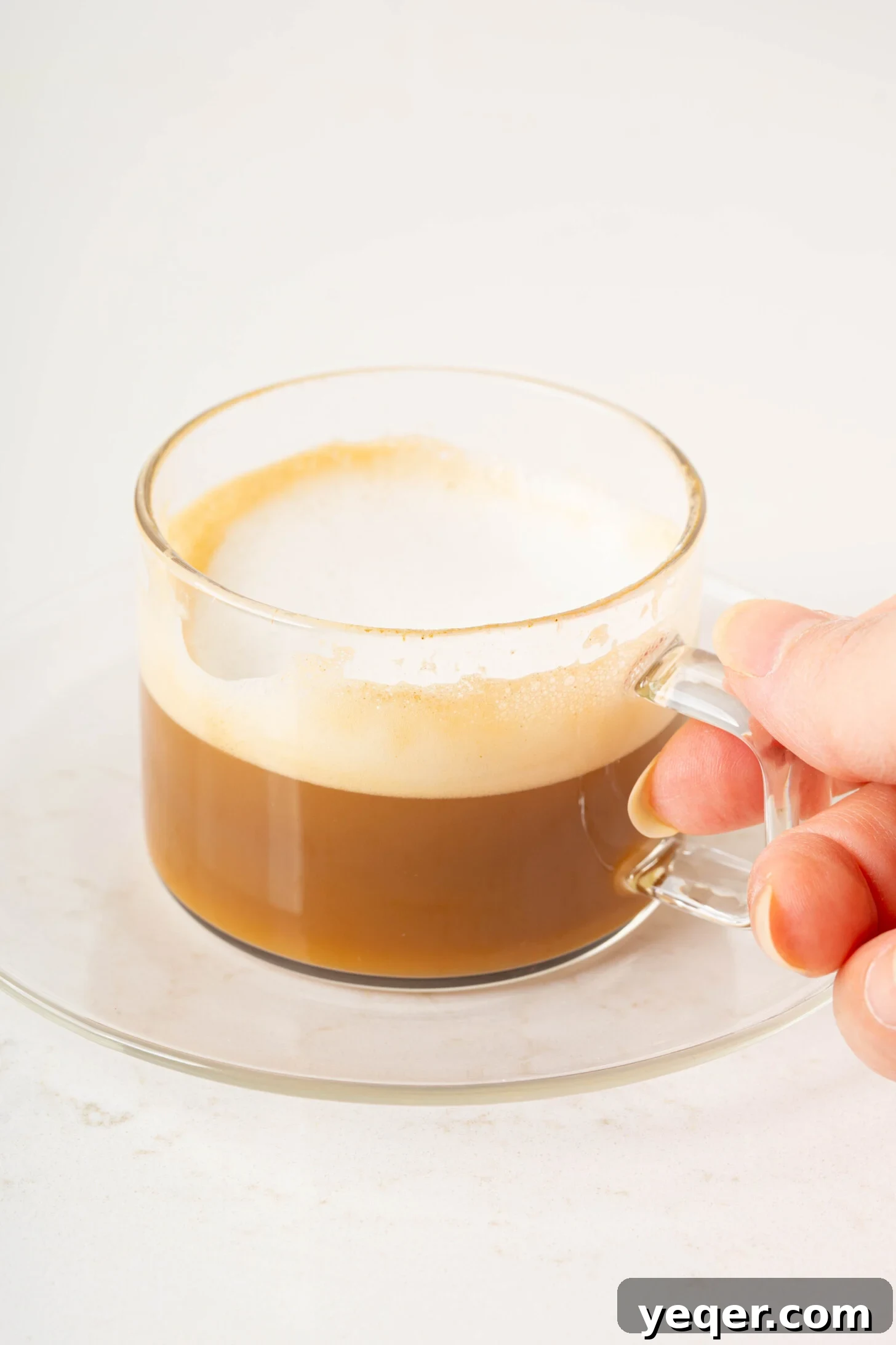 Your 10-Minute Cortado Perfect 1:1 Espresso and Steamed Milk 11 A beautifully crafted Cortado served in a clear glass on a wooden coaster, ready to be enjoyed.