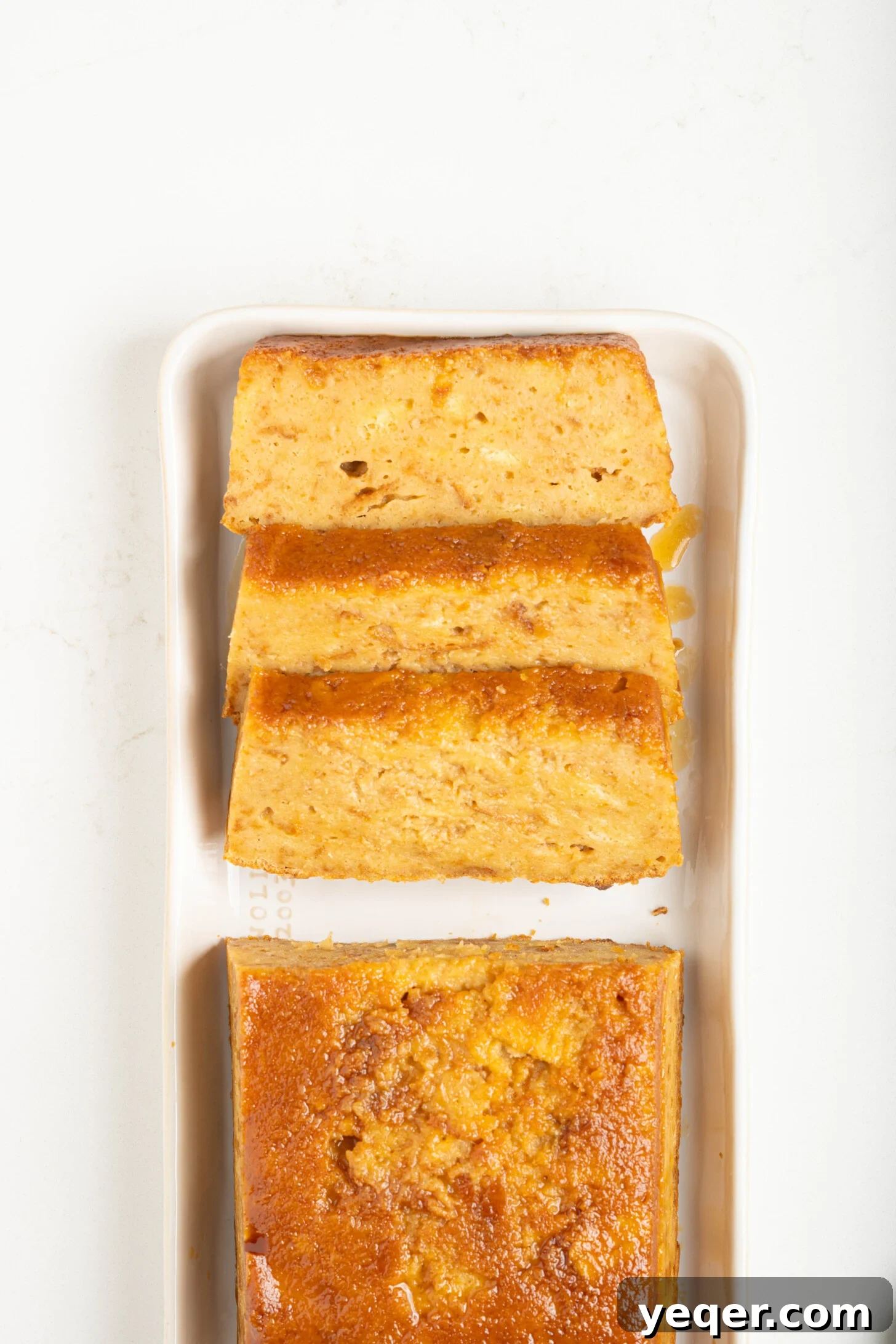 Puerto Rican Baked Bread Pudding 2 A perfectly sliced piece of Puerto Rican Budin, showcasing its moist texture and caramel topping on a white counter.