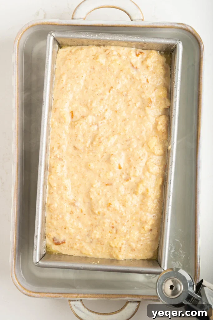 Puerto Rican Baked Bread Pudding 12 The budin in a loaf pan, submerged in a larger water bath, baking in the oven for gentle, moist cooking.