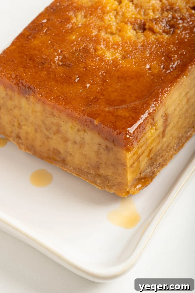 Puerto Rican Baked Bread Pudding 13 A slice of freshly baked Puerto Rican Budin, glistening with caramel, served on a plate for immediate enjoyment.