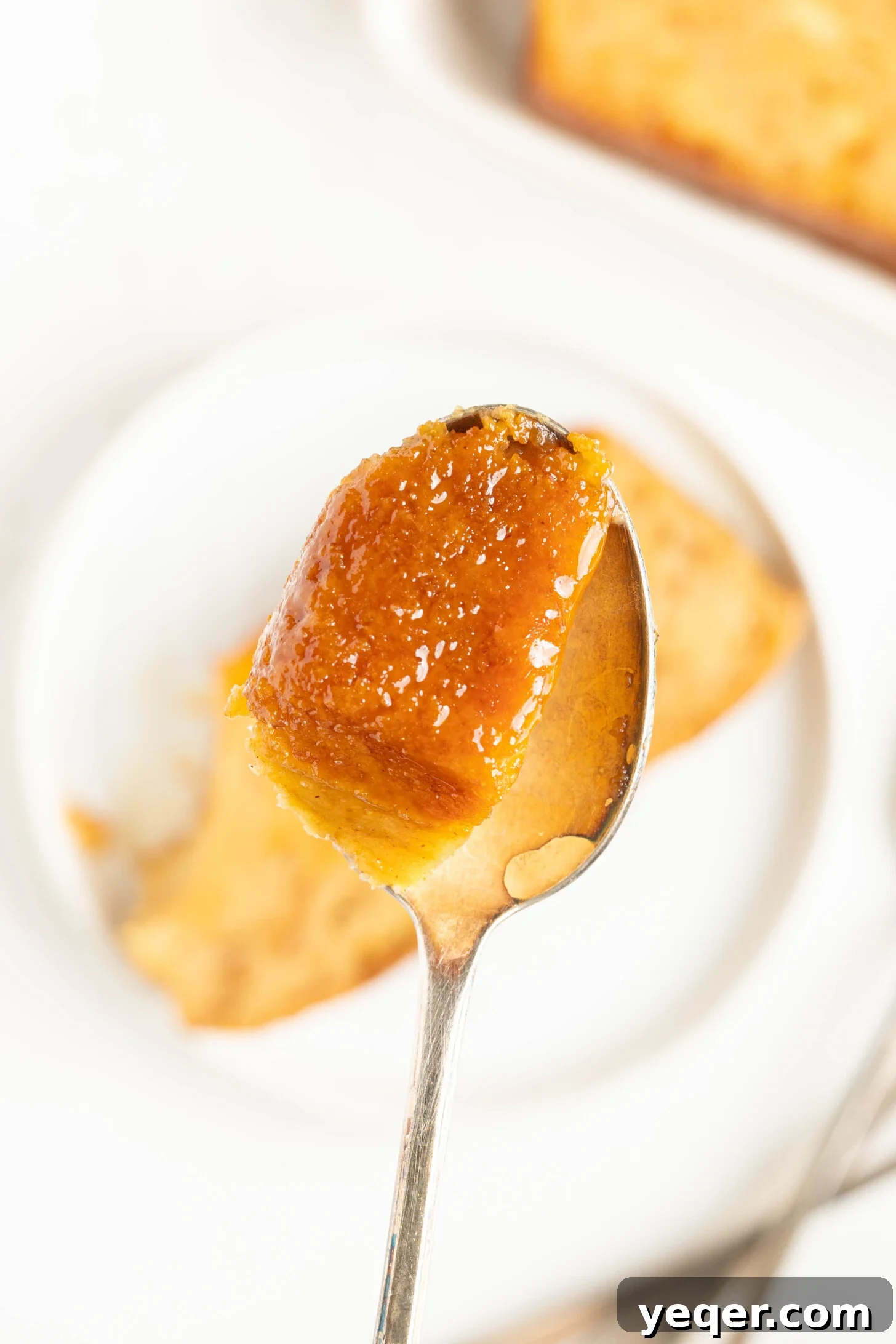 Puerto Rican Baked Bread Pudding 16 A spoon lifting a piece of moist, caramel-coated Puerto Rican Budin, showing its creamy texture.