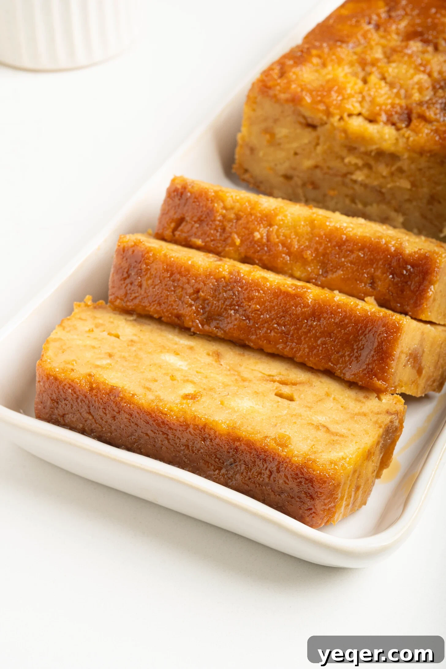 Puerto Rican Baked Bread Pudding 3 A delicious slice of Puerto Rican Budin served on a white plate, highlighting its golden caramel and soft interior.
