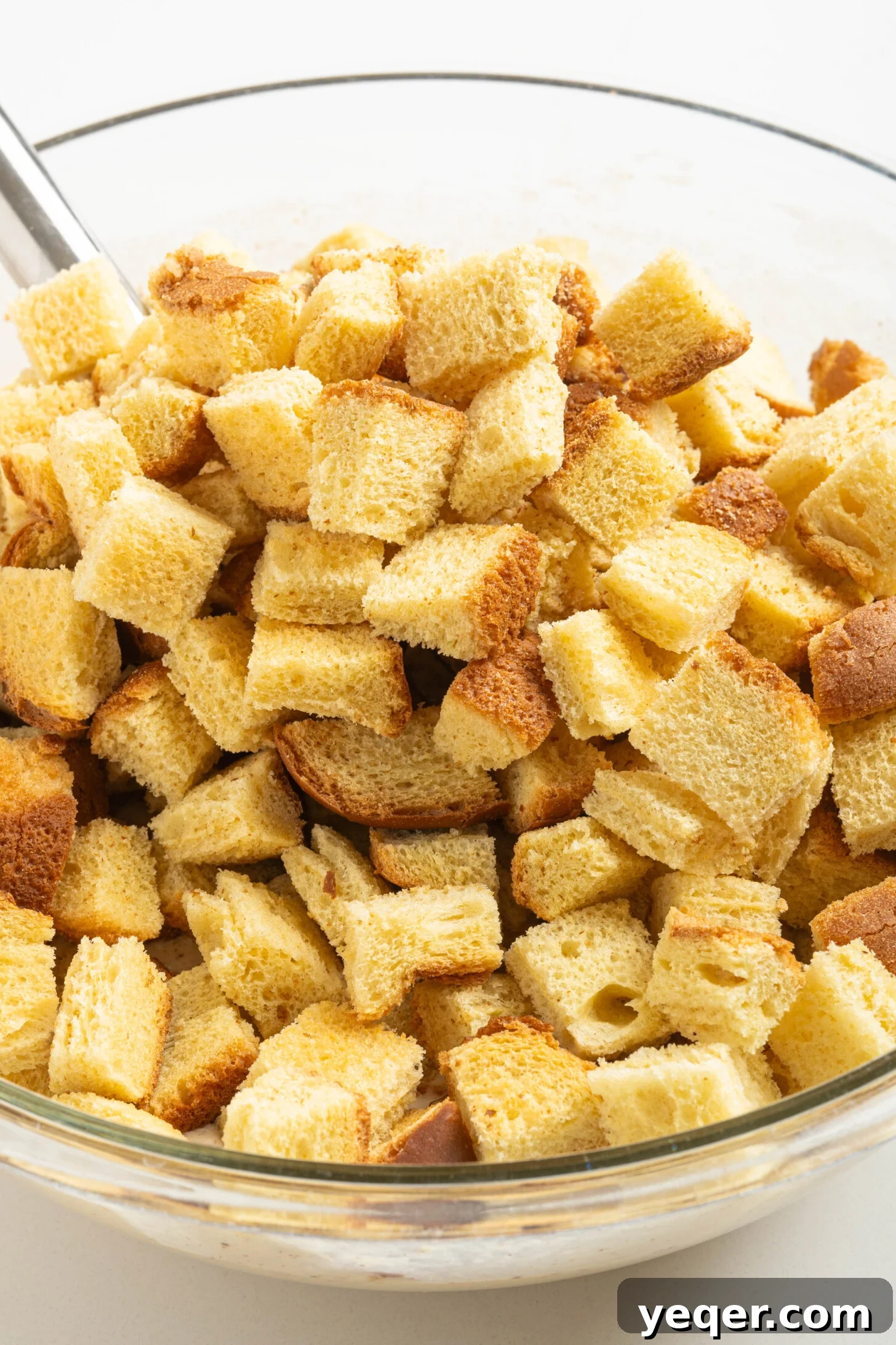 Puerto Rican Baked Bread Pudding 5 Cubed bread being thoroughly mixed into a creamy, spiced batter in a large bowl, demonstrating the mashing technique for Puerto Rican Budin.