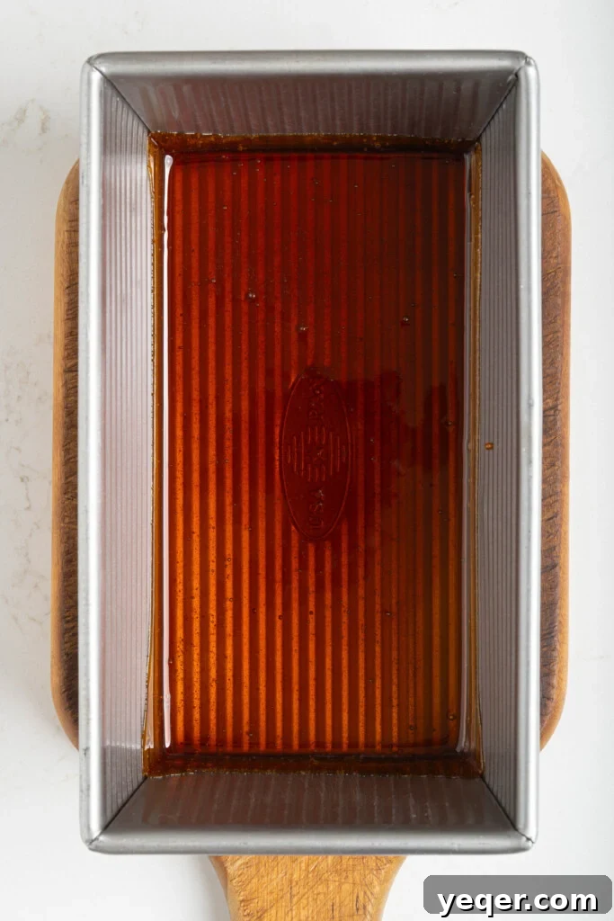 Puerto Rican Baked Bread Pudding 7 Golden caramel being carefully poured into the bottom of a loaf pan, ready to cool and solidify.