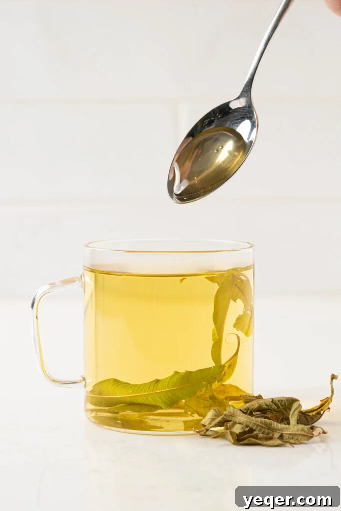 Invigorating Lemon Verbena Tea in 15 Minutes 5 A spoonful of honey being stirred into a cup of freshly brewed lemon verbena tea, suggesting a subtle sweetening option.