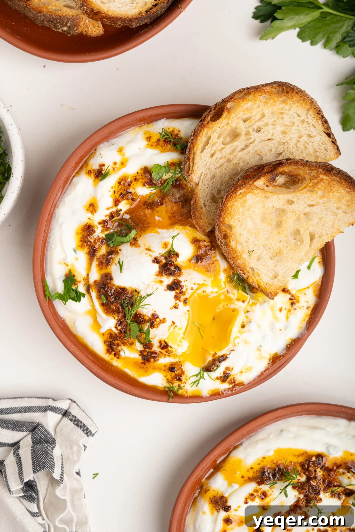 30-Minute Cilbir Turkish Eggs with Creamy Yogurt 2 Plates of Turkish eggs (Cilbir) with vibrant Aleppo pepper butter and fresh herbs, ready to be enjoyed.