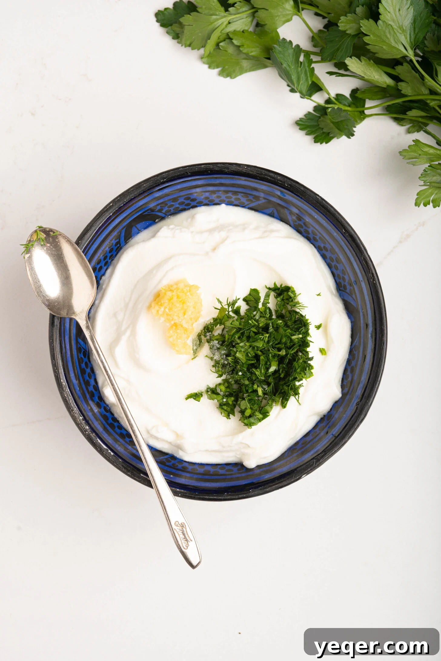 30-Minute Cilbir Turkish Eggs with Creamy Yogurt 4 A bowl of creamy Greek yogurt mixed with fresh herbs and grated garlic, ready for the Cilbir base.