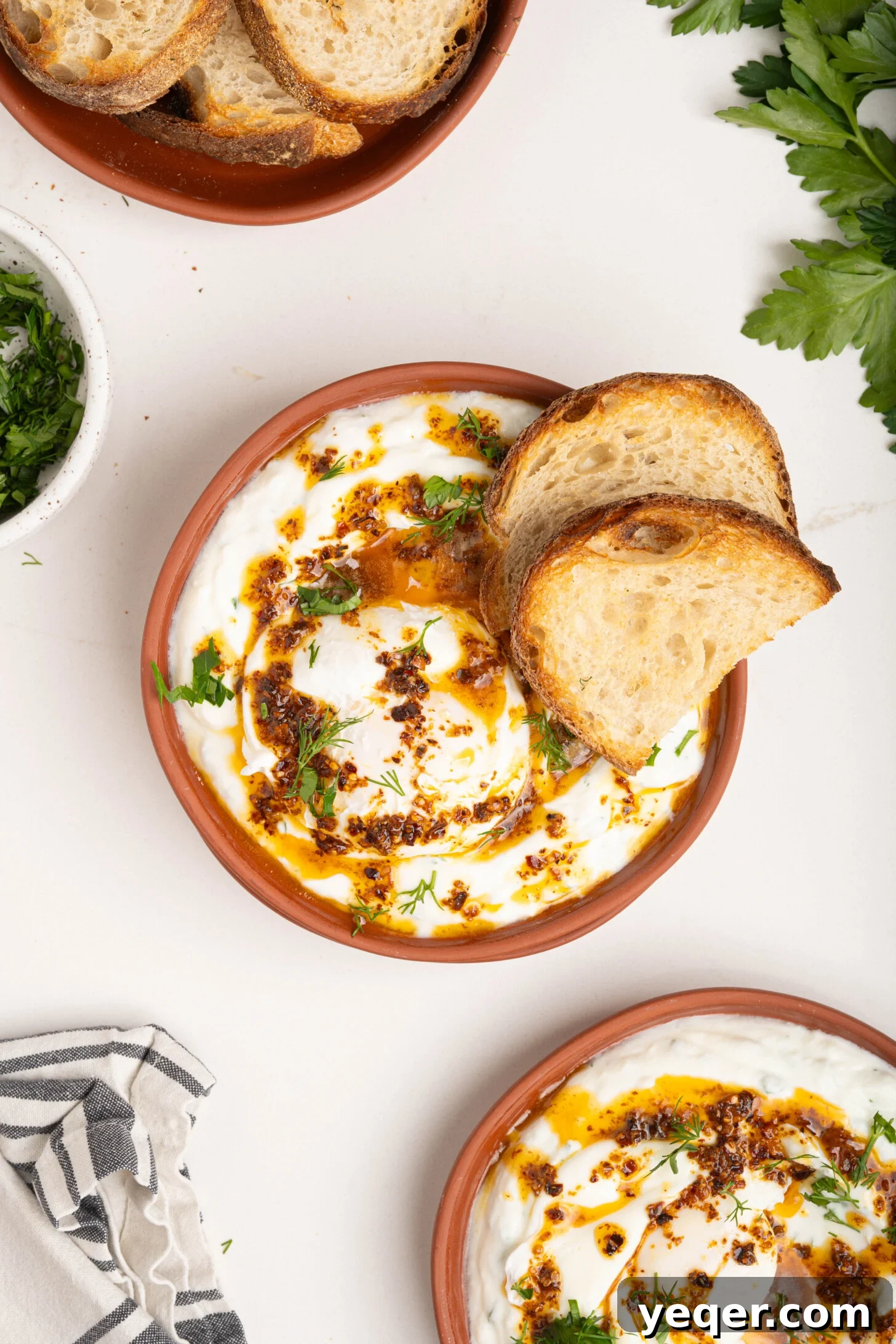 30-Minute Cilbir Turkish Eggs with Creamy Yogurt 9 Two plates of freshly prepared Turkish eggs (Cilbir) garnished with dill, ready to be served.