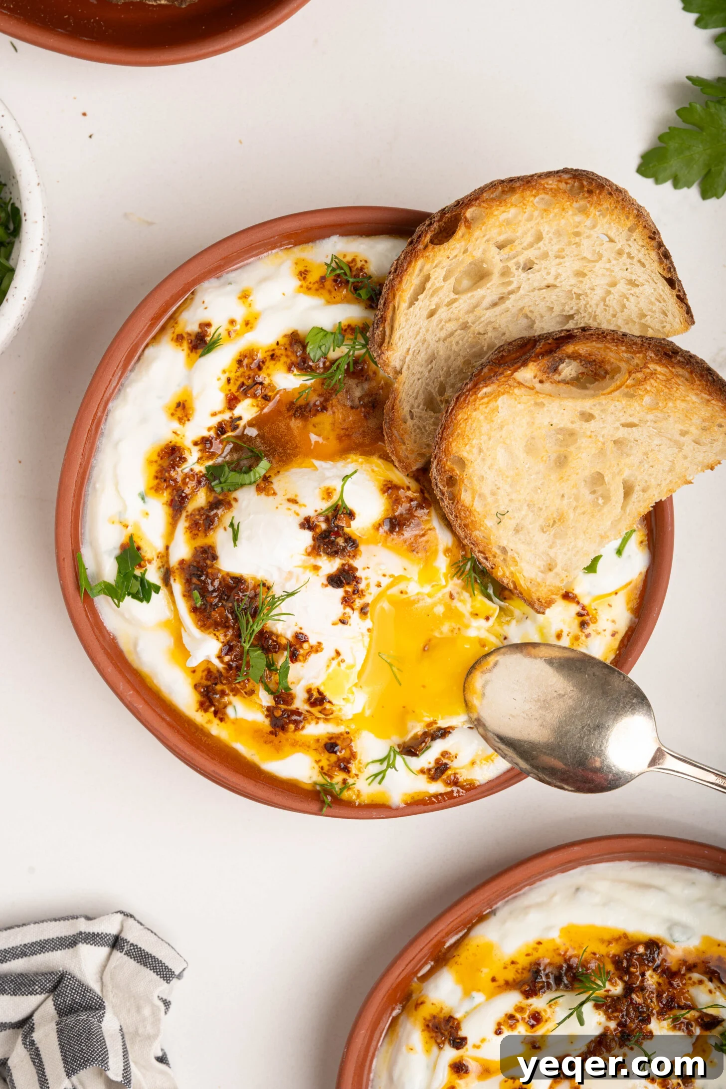 30-Minute Cilbir Turkish Eggs with Creamy Yogurt 10 A close-up of a plate of Turkish eggs, showcasing the runny yolk, garlic yogurt, and spiced butter.
