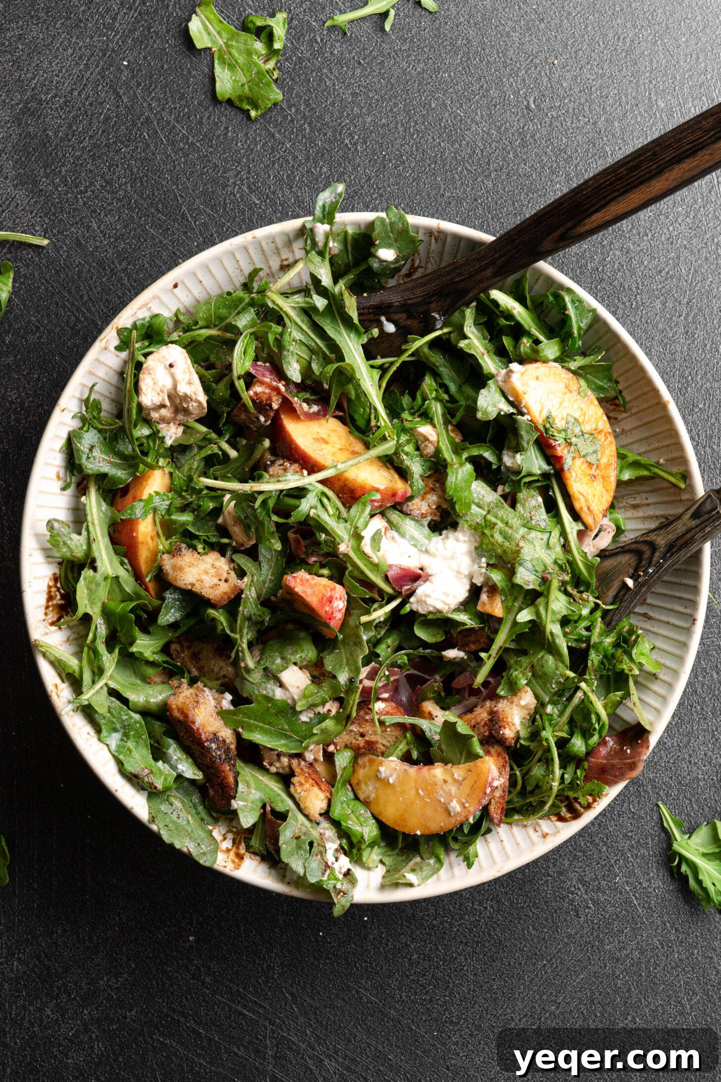 Decadent Peach Prosciutto Burrata Salad with Arugula and Crispy Croutons 2 A tossed burrata peach salad in a large white bowl, ready to be served.