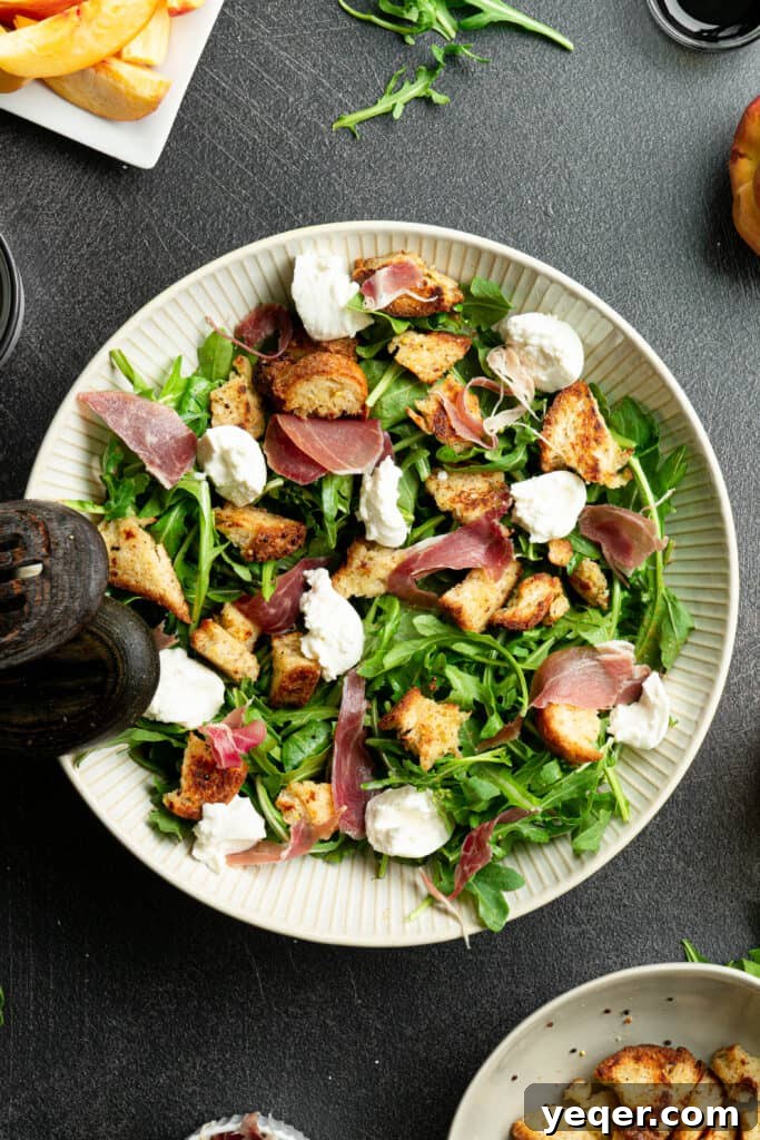 Decadent Peach Prosciutto Burrata Salad with Arugula and Crispy Croutons 7 Arugula with prosciutto, croutons, burrata, and dressing in a large white salad bowl, featuring the creamy burrata.