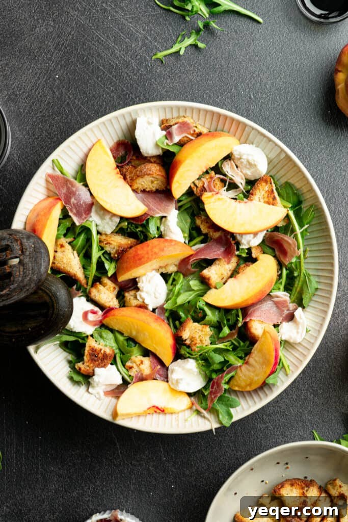 Decadent Peach Prosciutto Burrata Salad with Arugula and Crispy Croutons 8 Arugula with prosciutto, croutons, burrata, peaches, and dressing in a large white salad bowl, showcasing the final assembly.