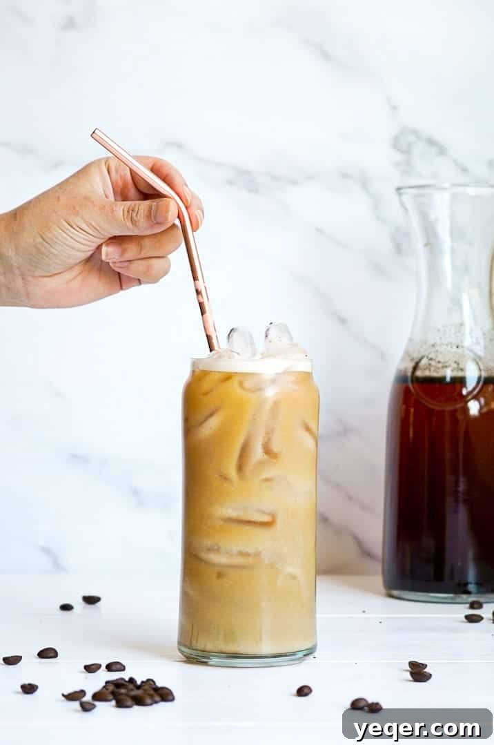 Smooth Cold Brew Overnight Delight 8 A hand placing a straw into a glass of cold brew coffee, inviting you to take a refreshing sip.