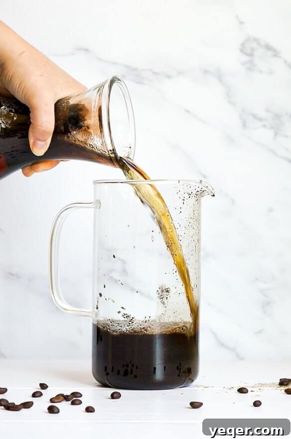 Smooth Cold Brew Overnight Delight 4 A bottle pouring Overnight Cold Brew Coffee concentrate into another container for easy storage and serving.