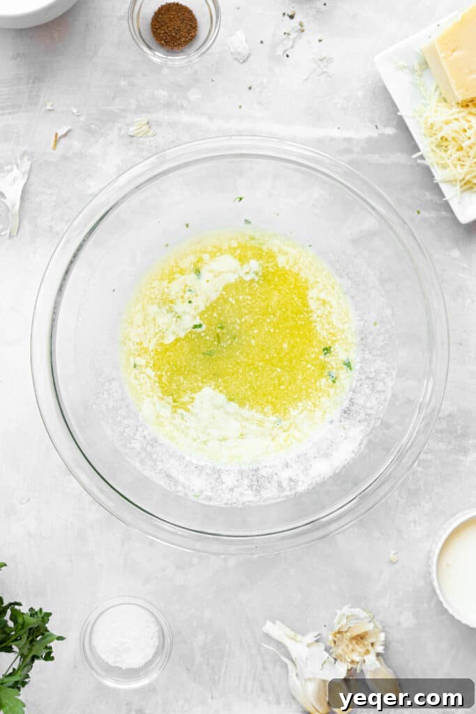 A glass bowl of melted butter with garlic and herbs.