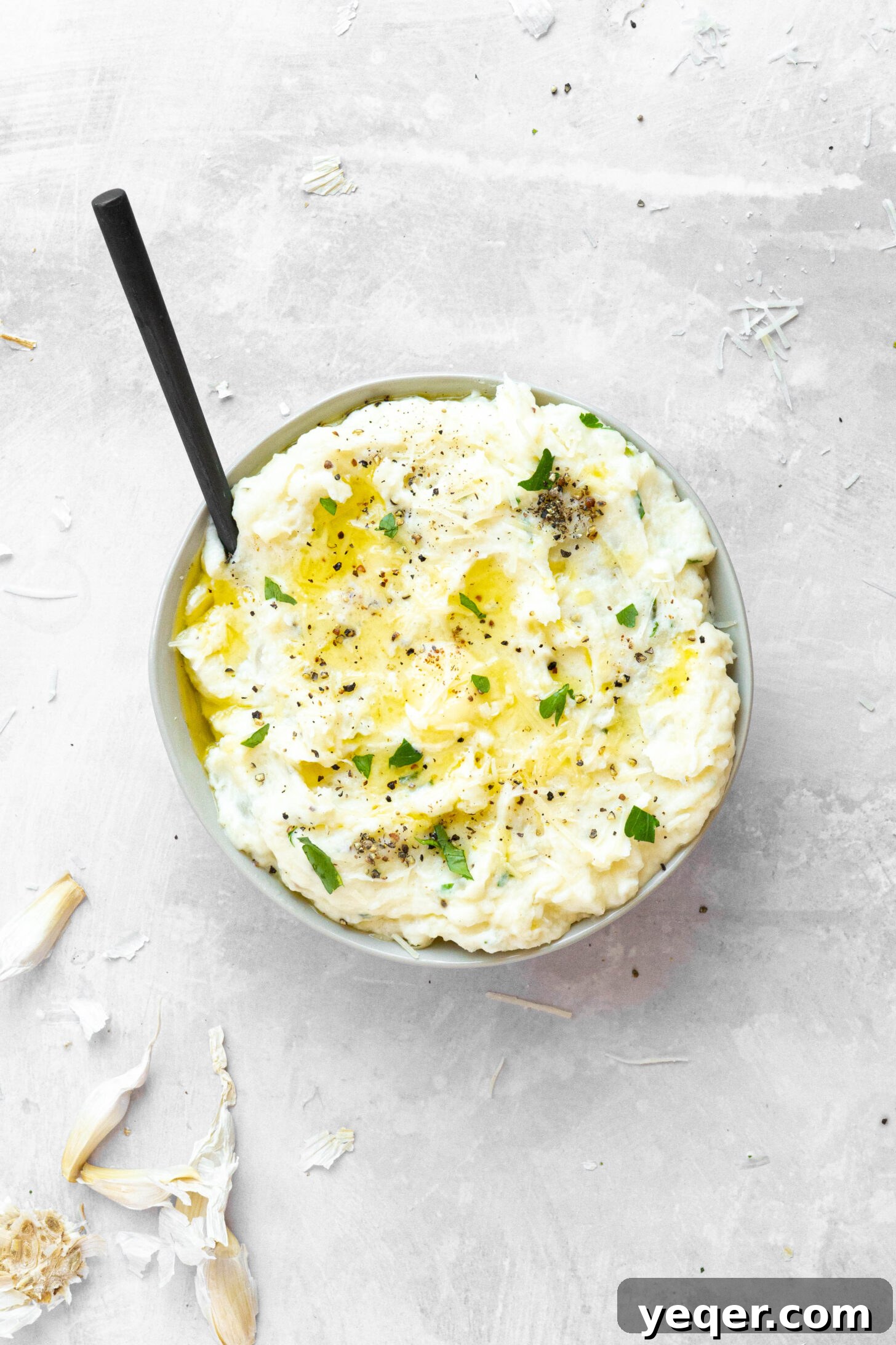 A bowl of mashed potatoes with a black spoon.
