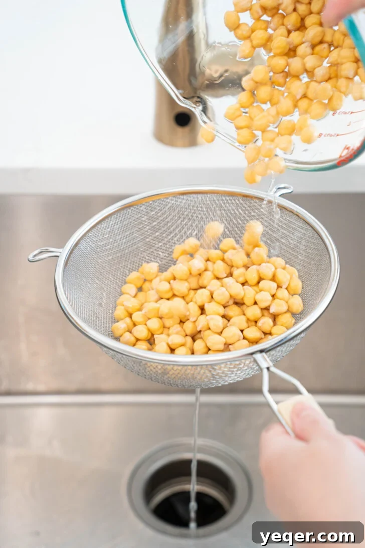 The Foolproof Soak and Boil Method for Perfect Dried Chickpeas 5 chickpeas being strained over a sink