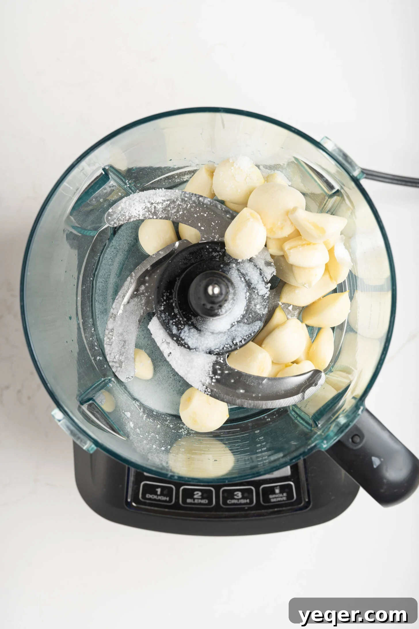 Fluffy 5-Ingredient Garlic Toum 8 A food processor with garlic and salt