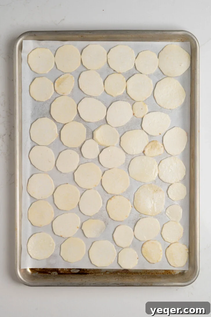 Crispy Taro Chips 30 Minutes Oven and Air Fryer 11 Taro chips tossed with oil and salt, arranged in a single layer on a parchment-lined baking sheet.