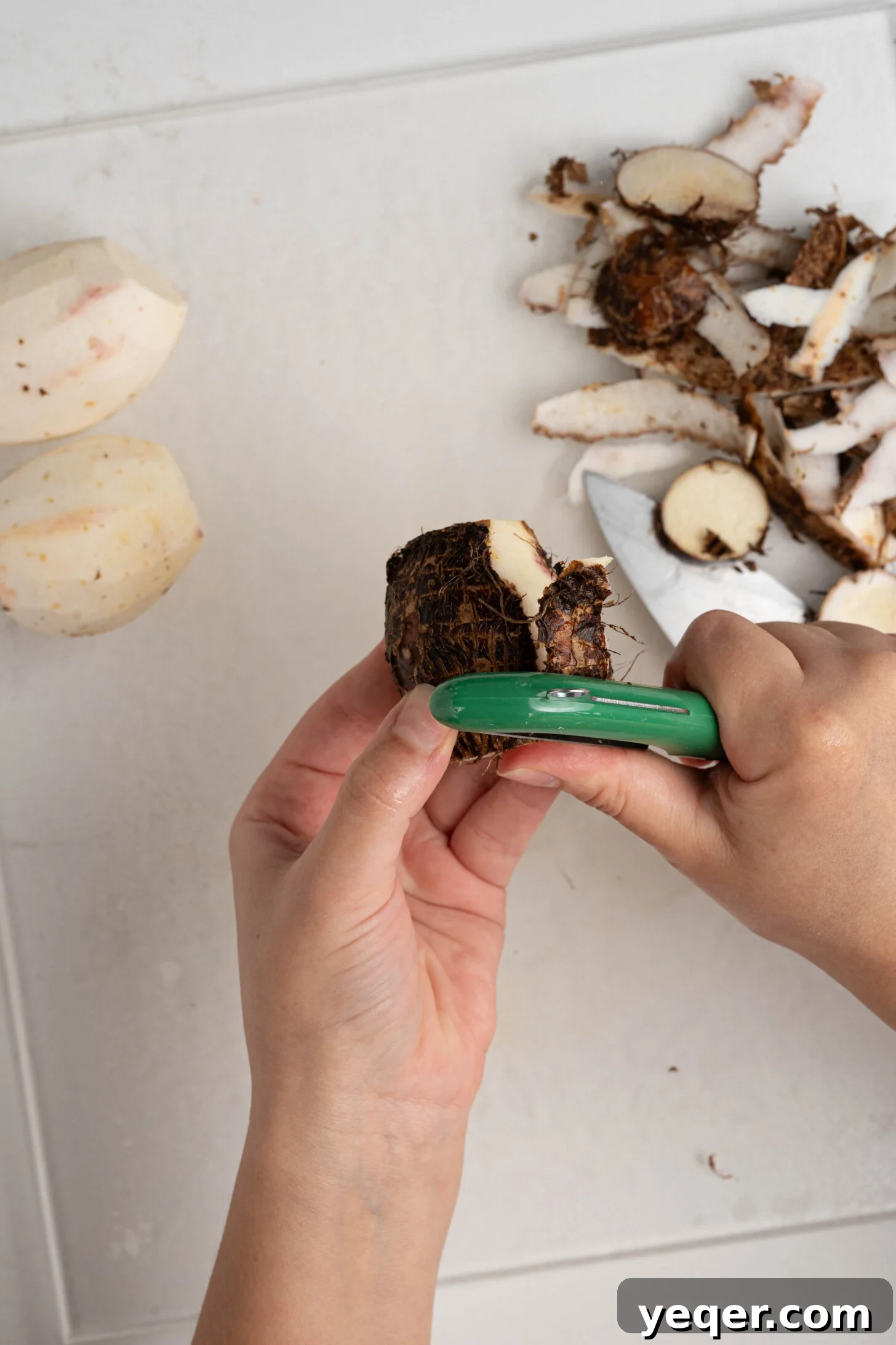 Crispy Taro Chips 30 Minutes Oven and Air Fryer 13 A person carefully peeling a taro root with a sharp knife on a cutting board, illustrating the preparation step.