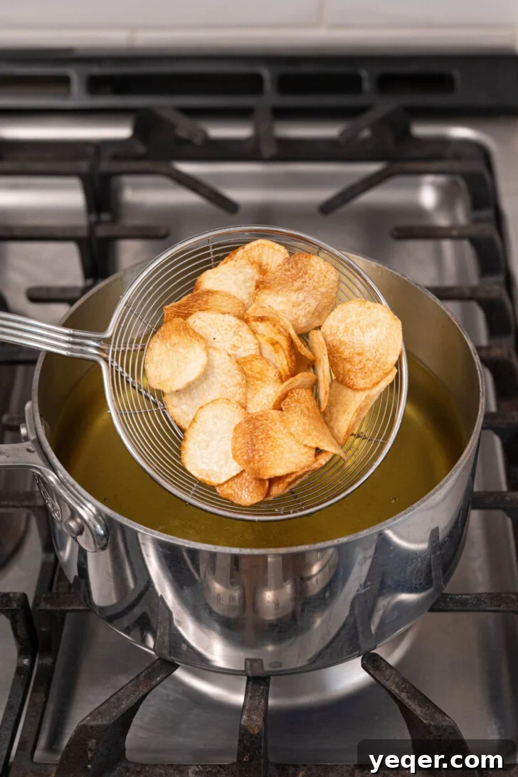 Crispy Taro Chips 30 Minutes Oven and Air Fryer 7 Freshly fried taro chips draining on paper towels, with a sprinkle of salt.