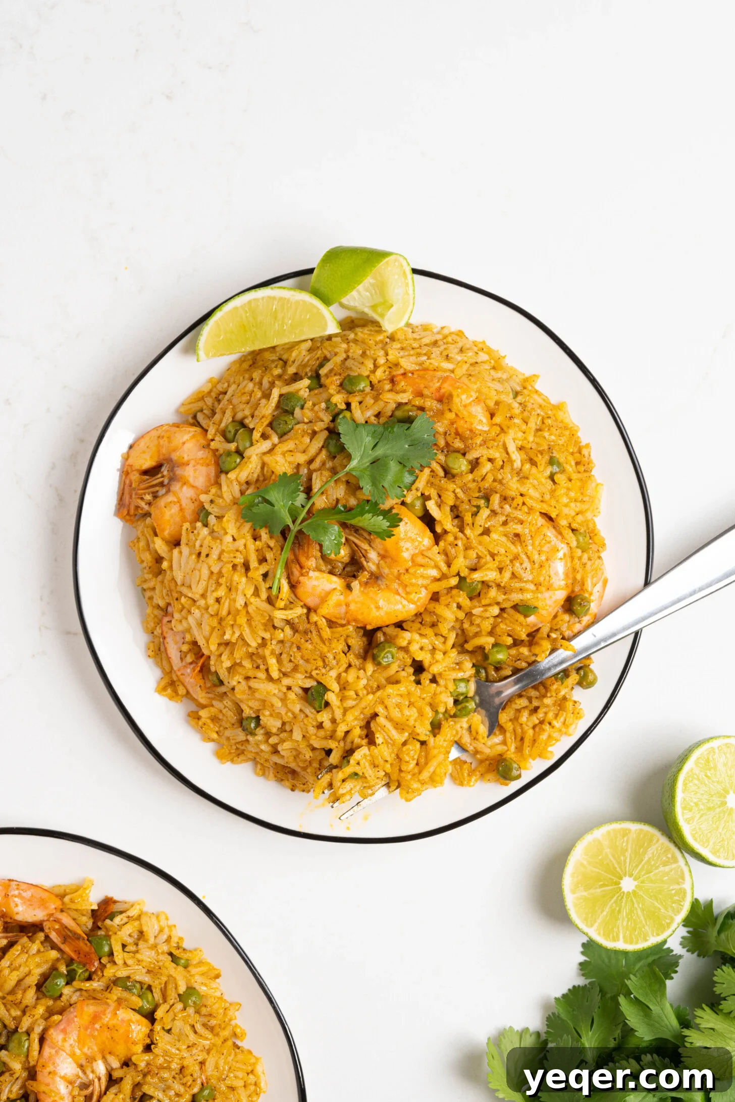 Vibrant Puerto Rican Arroz con Camarones 2 A serving of fluffy red rice with shrimp on a white plate, garnished with fresh cilantro.