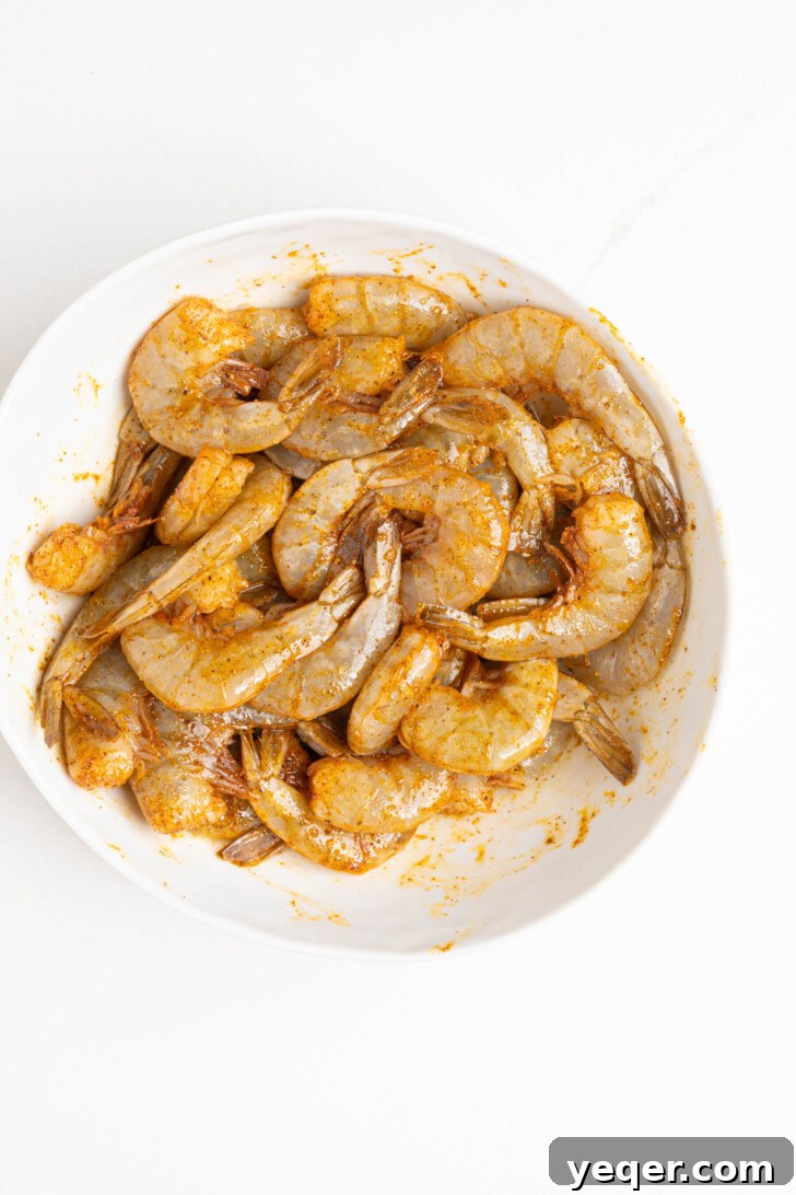Vibrant Puerto Rican Arroz con Camarones 6 Raw shrimp seasoned with sazon and melted butter in a bowl.