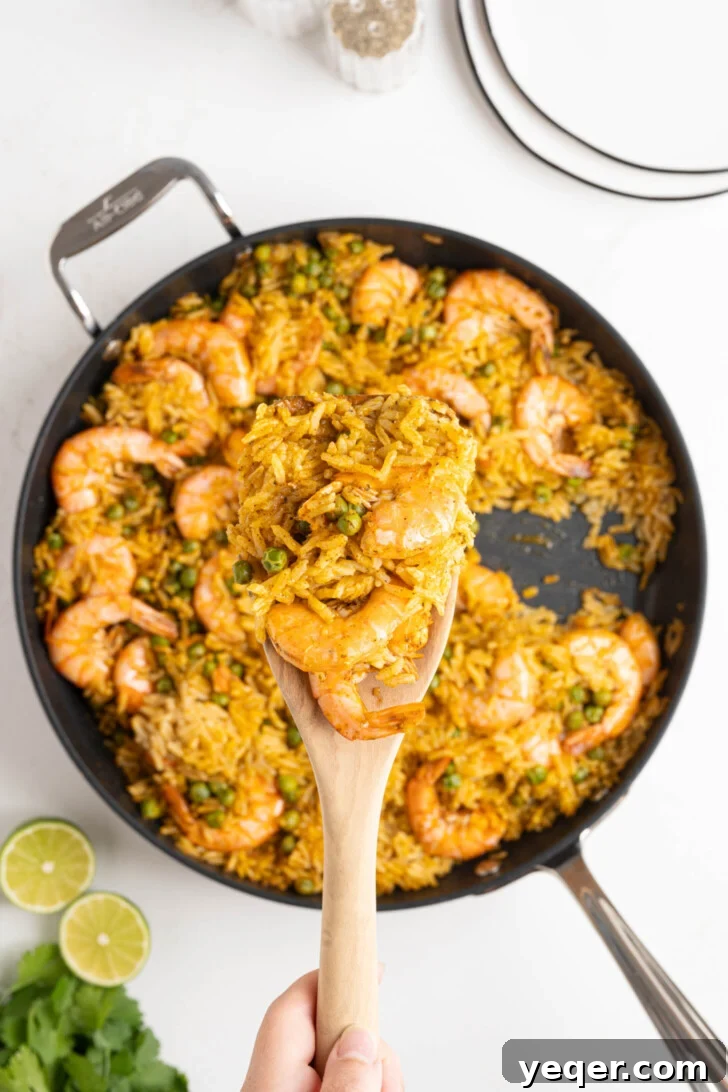 Vibrant Puerto Rican Arroz con Camarones 8 A spoonful of fluffy red rice and shrimp being served from the pan.