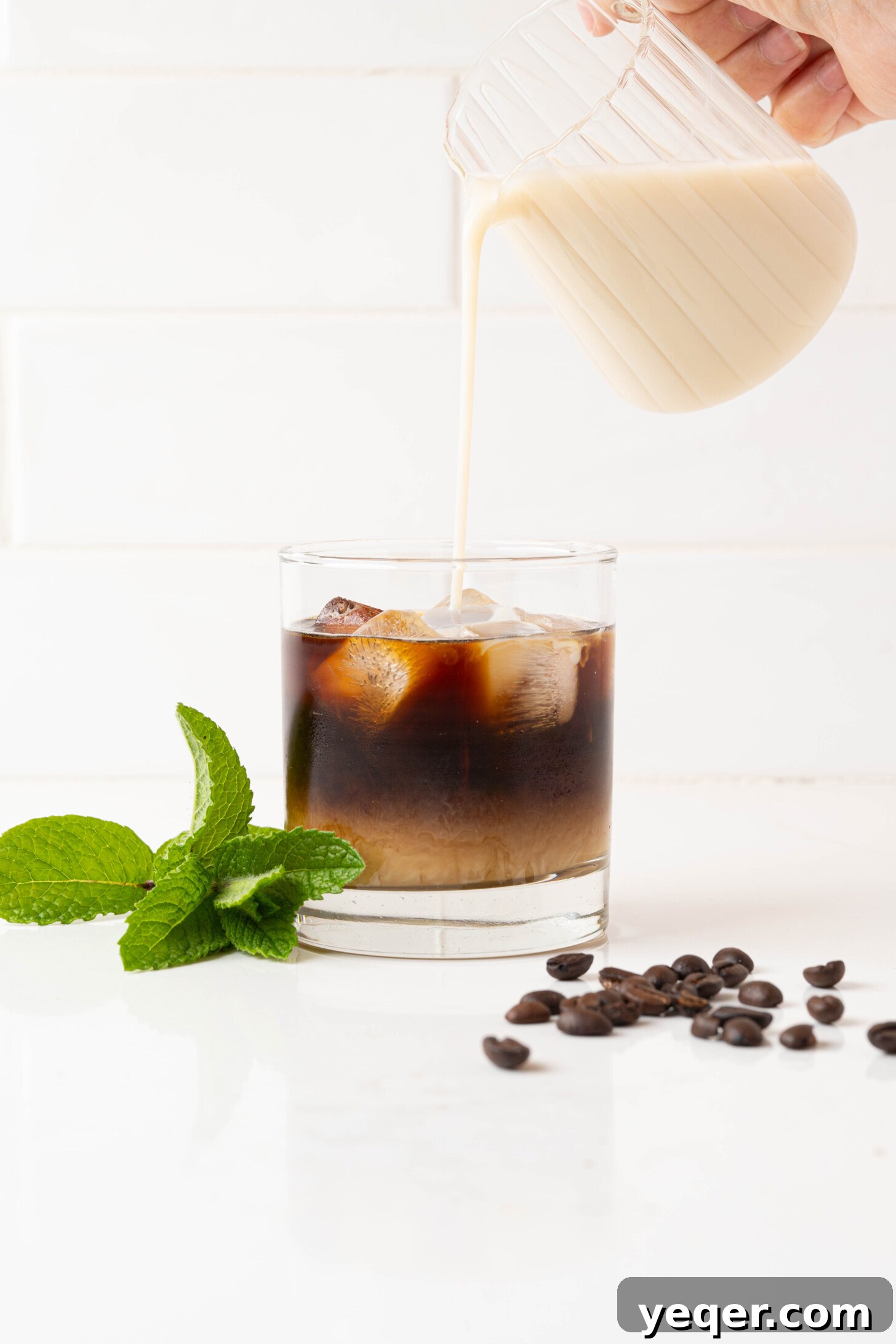 Easy Philz Style 5 Ingredient Coffee Mint Mojito 7 Creamy milk pouring into a glass of coffee mint mojito, creating a beautiful swirl.