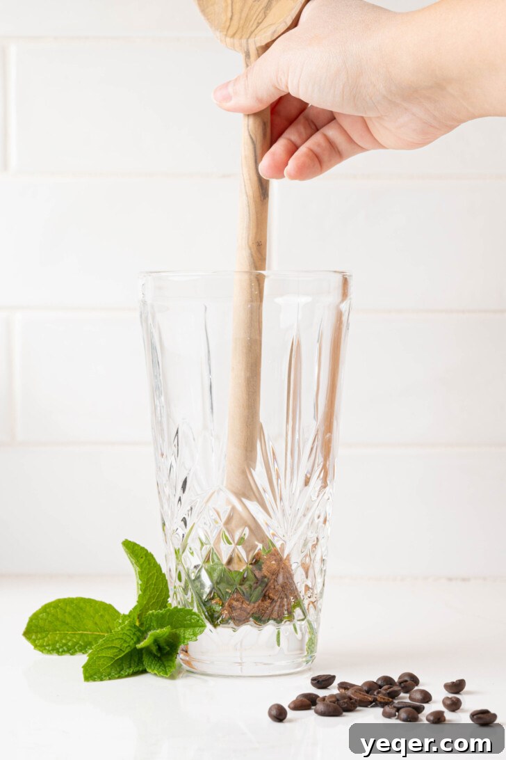 Easy Philz Style 5 Ingredient Coffee Mint Mojito 4 Fresh mint leaves and brown sugar being gently muddled together in a clear glass.