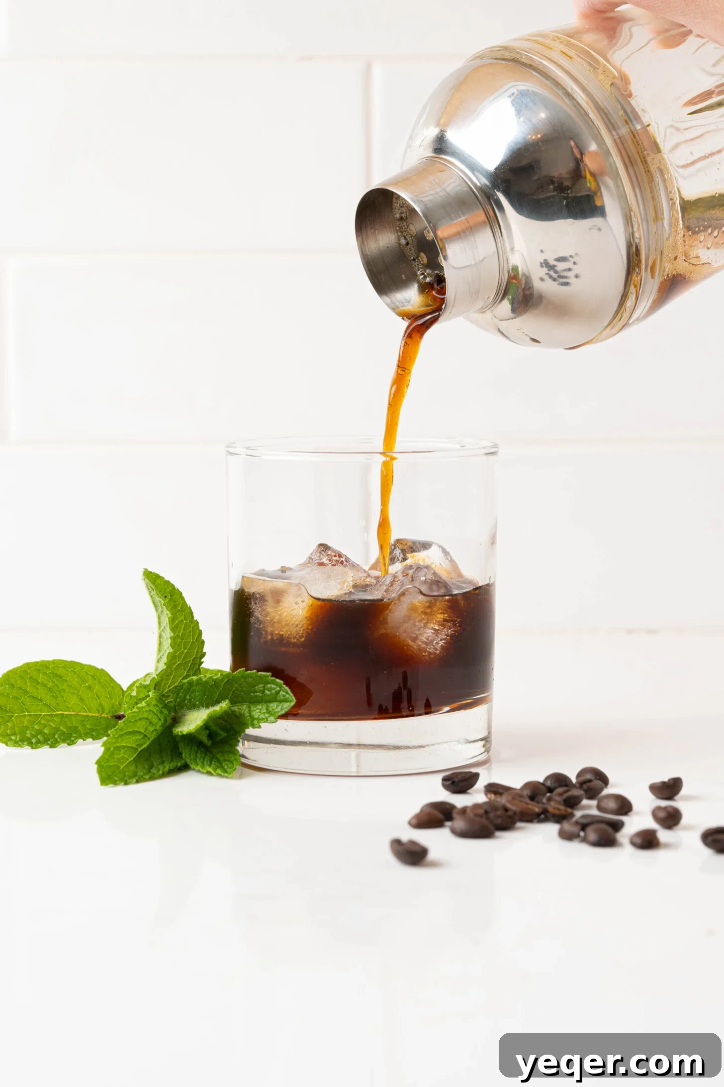 Easy Philz Style 5 Ingredient Coffee Mint Mojito 6 A stream of freshly mixed coffee mint mojito pouring from a shaker into a glass filled with ice.