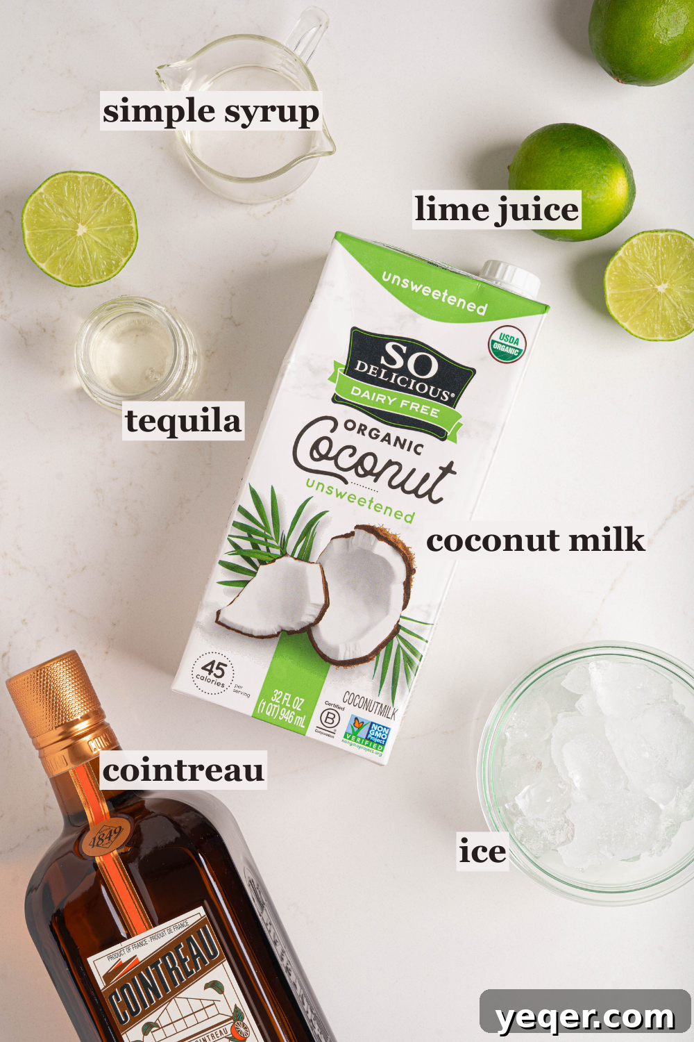 Effortless Silky Coconut Margarita 3 Fresh ingredients for a coconut margarita including coconut milk, limes, and a shaker on a counter.