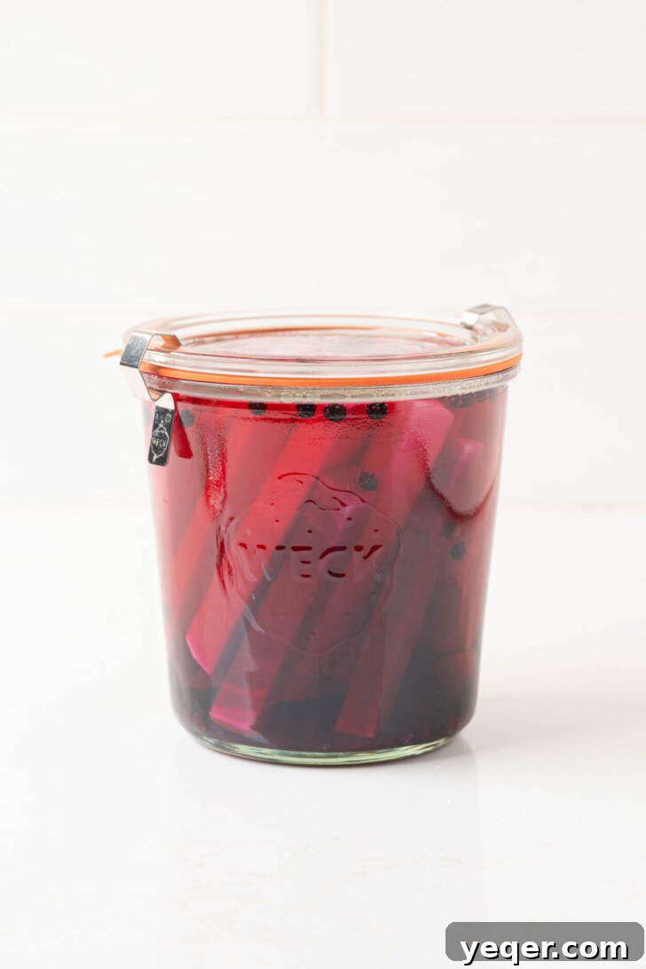 Easy 5-Ingredient Pink Pickled Turnips 8 A sealed jar of pink pickled turnips sitting on a countertop, undergoing the pickling process.
