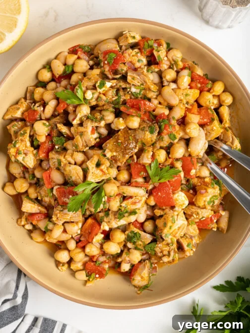 A beautifully presented bowl of Moroccan dense bean salad with roasted chicken, garnished with fresh herbs.