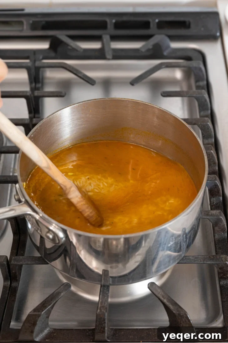 Fluffy 30-Minute Yellow Rice 6 White rice being stirred into the seasoned oil and sofrito mixture in a pot.