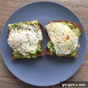 Hello World, Have Some Avocado Toast! 2 Two perfectly prepared pieces of avocado toast, each topped with a fried egg and a sprinkle of salt and pepper.